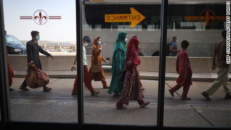 Afghans board buses at Dulles International Airport that will take them to a processing center after being evacuated from Kabul following the Taliban takeover of Afghanistan in August 2021.