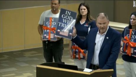 A Christian wireless provider has donated framed posters of the motto &quot;In God We Trust,&quot; seen here at a meeting of suburban Dallas school district, which will be obliged by a new state law to display them.
