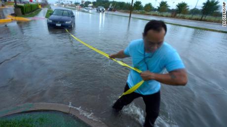 Mon Lun pulls a strap to his water stall car Monday before towing out of retreating flood water in Dallas.