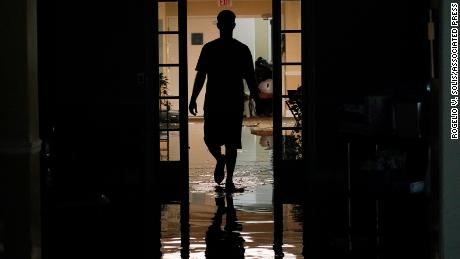 A relative walks through the Peach Tree Village nursing home to collect family belongings after the facility was flooded Wednesday.
