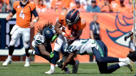 Denver Broncos running back Royce Freeman (center) gets taken down by Griffin (49) and his brother, Shaquill (26), at Broncos Stadium at Mile High. 