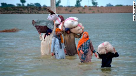 A displaced family wades through a flooded area in Jaffarabad, a district of Pakistan&#39;s southwestern Baluchistan province, on August 24.