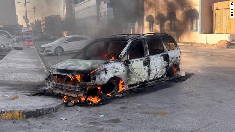 2022年8月27日、リビアのトリポリで衝突が発生している間、車が通りで燃えている。 