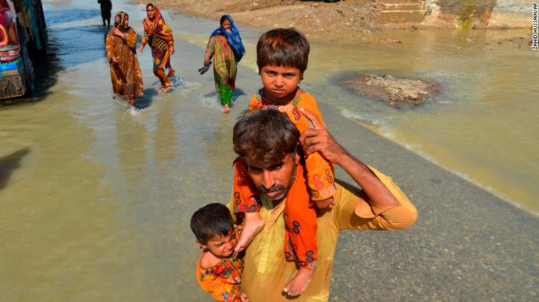 A displaced man carries his daughters from his flood-hit home in Jaffarabad, a district of Pakistan&#39;s southwestern Baluchistan province on Saturday. 