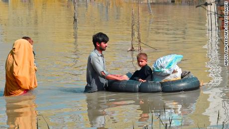 A family wades through a flood-hit area following heavy monsoon rains in Charsadda district of Khyber Pakhtunkhwa on August 29, 2022.