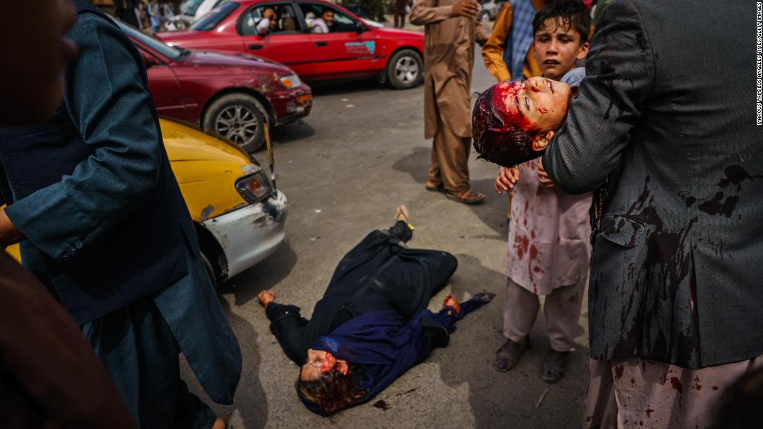 A man carries a bloodied child as a wounded woman lies on the street after Taliban fighters fired guns and lashed out with whips, sticks and sharp objects to control a crowd outside the airport in Kabul in August 2021. &quot;The violence was indiscriminate,&quot; Los Angeles Times photographer Marcus Yam told CNN. &quot;I even watched one Taliban fighter, after firing some shots in the general direction of the crowd, smiling at another Taliban fighter — as though it were a game to them or something.&quot;