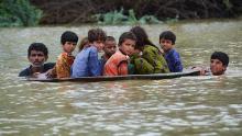 A man helps children navigate floodwaters using a satellite dish in Balochistan, Pakistan, on Friday, August 26.
