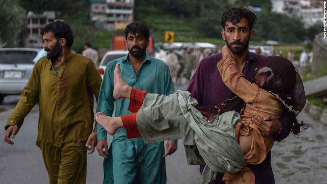 A man carries his sick daughter along a road damaged by floodwaters in Pakistan's northern Swat Valley on August 27.