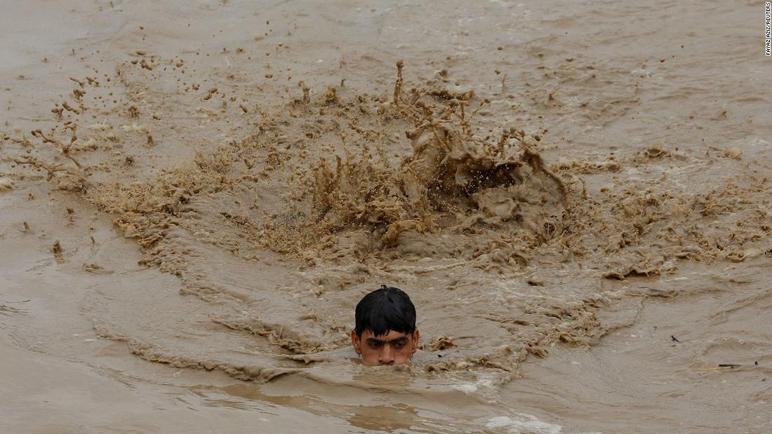 A man swims in floodwaters while heading for higher ground in Charsadda, Pakistan, on August 27.