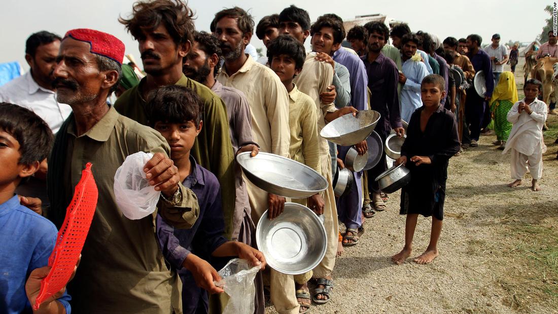 Flood-affected people stand in a long line for food distributed by Pakistani Army troops in Rajanpur on August 27.