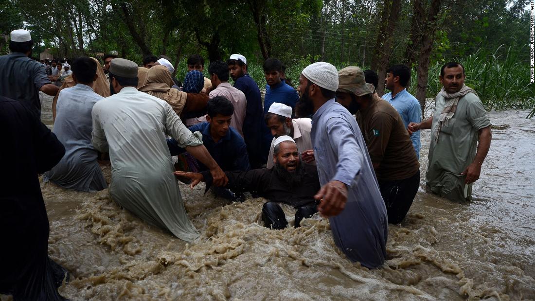 People walk through floodwaters in Dagai Mukram Khan, Pakistan, on August 26.