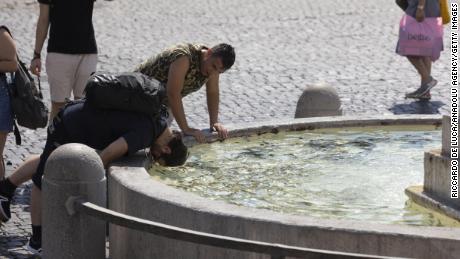 People cool off at a fountain in Rome's Piazza del Popolo in early August.