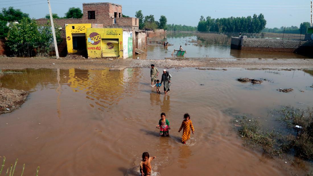 People wade through floodwaters in Charsadda, Pakistan, on August 31.