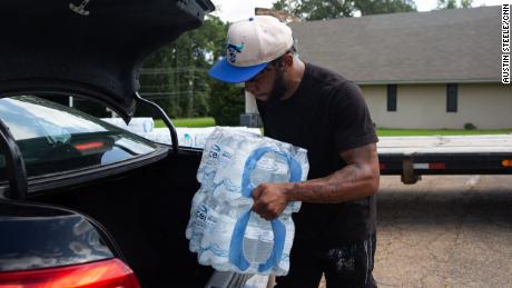 Malcolm Pickett loads water into a resident&#39;s car outside of New Jerusalem Church in Jackson, Mississippi, on August 31.