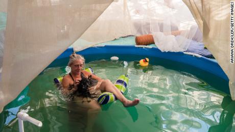 La galerie d'art Dot of House of Dots se détend dans sa piscine avec son chien alors qu'ils se rafraîchissent au milieu d'une vague de chaleur à Slab City près de Niland, en Californie, mercredi. 