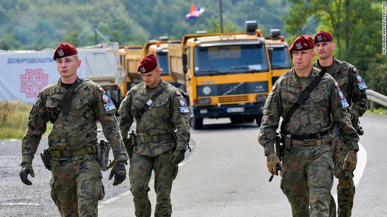 Polish soldiers, part of a NATO peacekeeping mission in Kosovo, pass through barricades near the border crossing between Kosovo and Serbia on September 28, 2021.