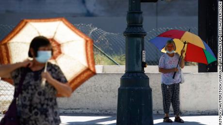 People walk with umbrellas for shade in Los Angeles on Thursday.