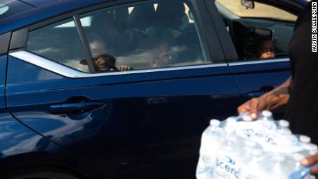 A child watches as Malcolm Pickett distributes water outside New Jerusalem Church in Jackson, Mississippi, on August 31.