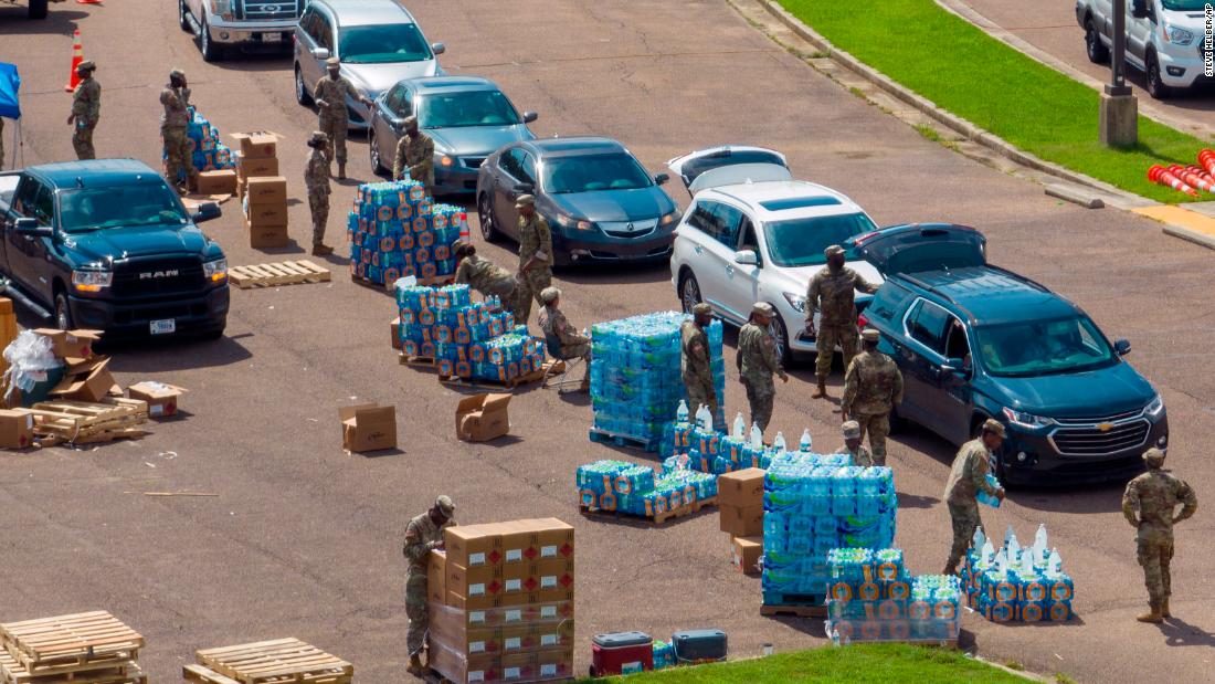 the National Guard places a case of water in the back of a car at the State...