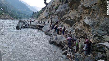 Residents climb rocks to avoid flooding in the Kalam Valley, northern Pakistan, on September 4, 2022.
