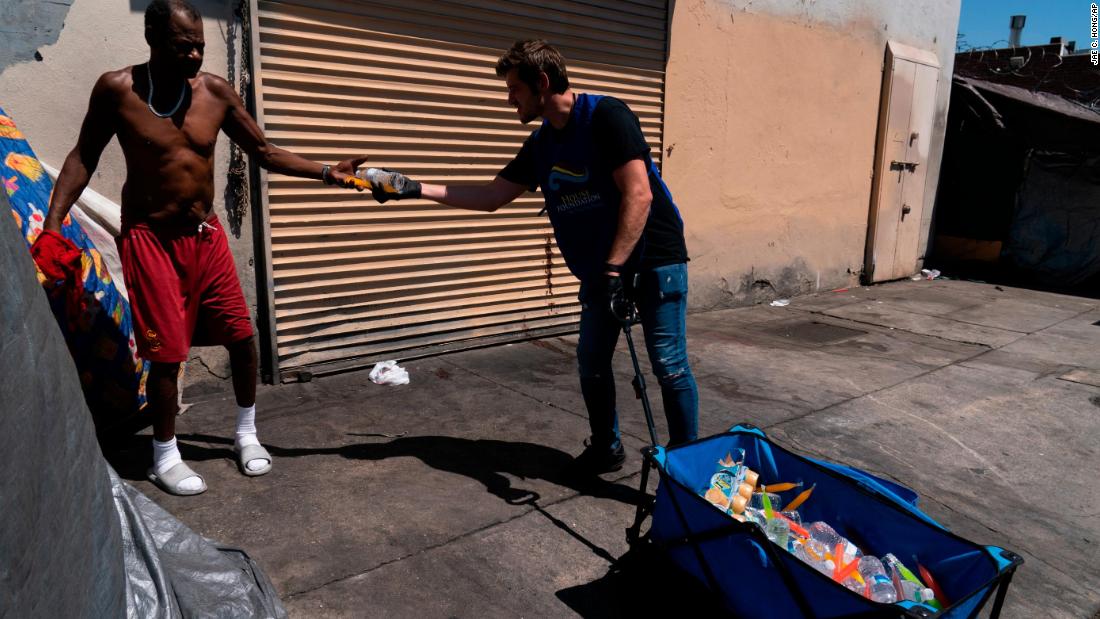 Paskal Pawlicki from My Friend&#39;s House Foundation hands a bottle of water to a man in the Skid Row area of Los Angeles on August 31.