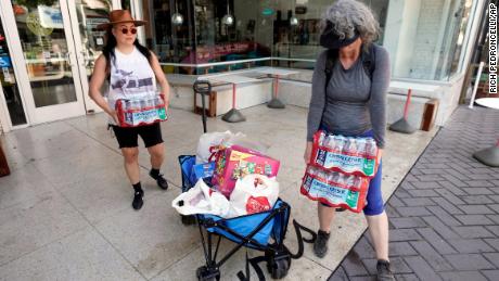 Debbie Chang po lewej i Kim Burrell ładują na wózek butelkowaną wodę, aby we wtorek rozprowadzić ją wśród ludzi na ulicy w Sacramento.