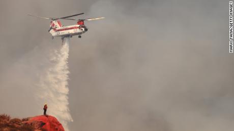 A firefighting helicopter performs a water drop as the Fairview Fire burns Tuesday near Hemet, California. 