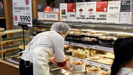 A Homeplus worker putting buckets of fried chicken out for sale. The hypermarket has created pressure on other stores to follow suit on its popular discounts.
