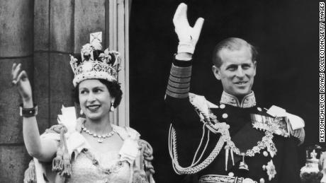 Queen Elizabeth II and the Duke of Edinburgh wave at the crowds from the balcony at Buckingham Palace after Elizabeth&#39;s coronation, on June 2, 1953. 