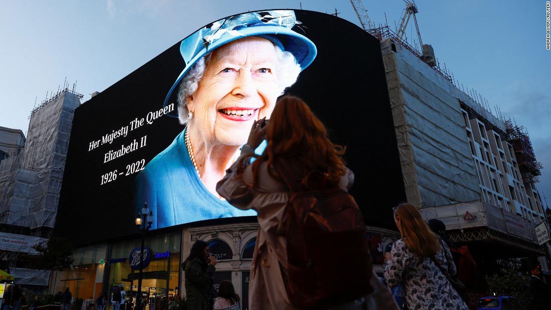 People take photos with their phones as an image of the Queen is displayed in London&#39;s Piccadilly Circus on Thursday, September 8.