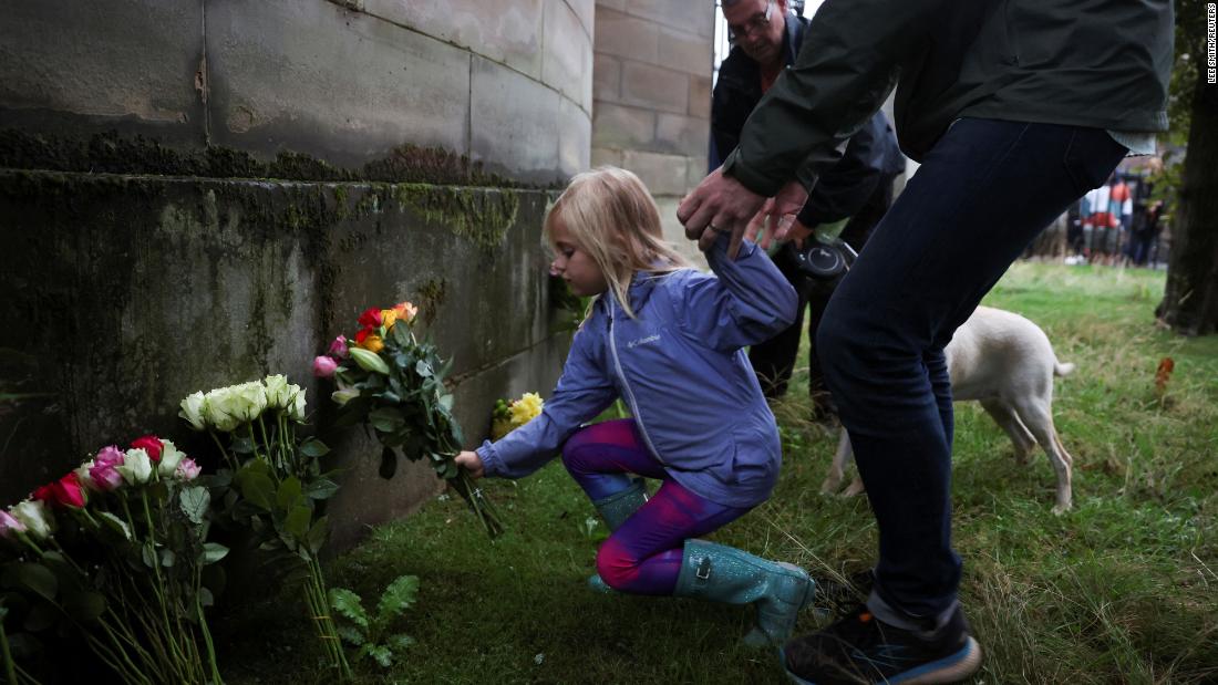 A child places flowers outside the Palace of Holyroodhouse in Edinburgh, Scotland.