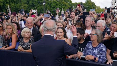 Britain&#39;s King Charles III, back to camera, greets well-wishers at Buckingham Palace.