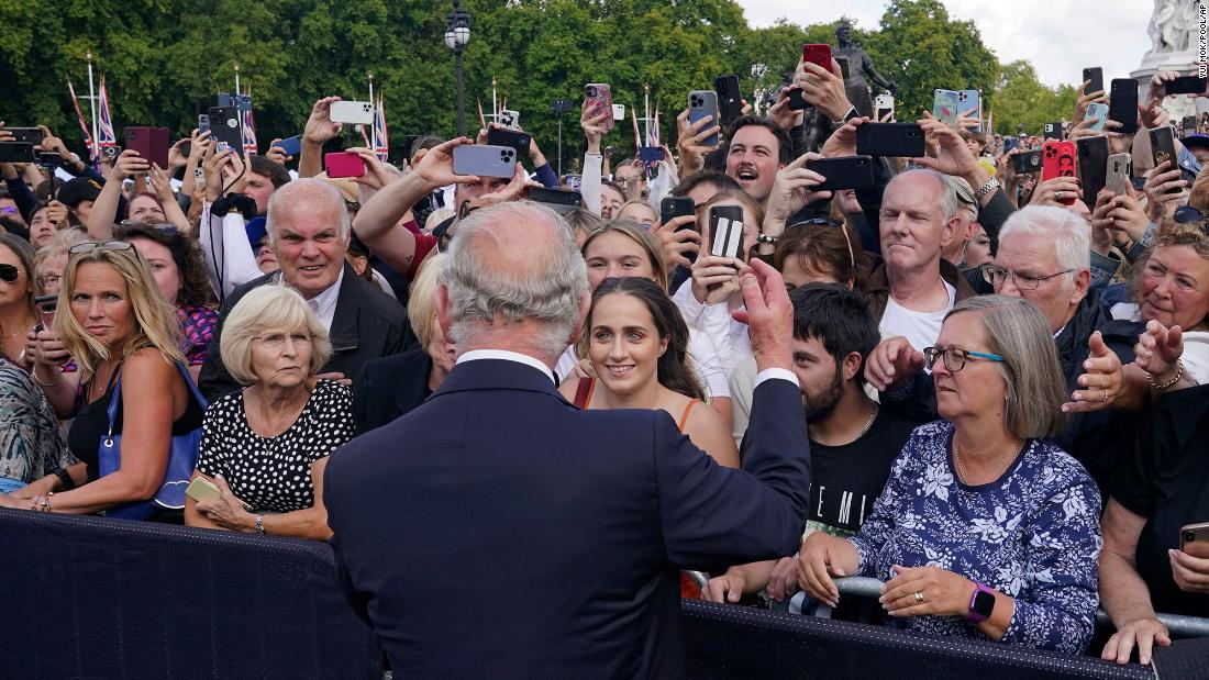 Charles greets well-wishers as he walks by the gates of Buckingham Palace on Friday.