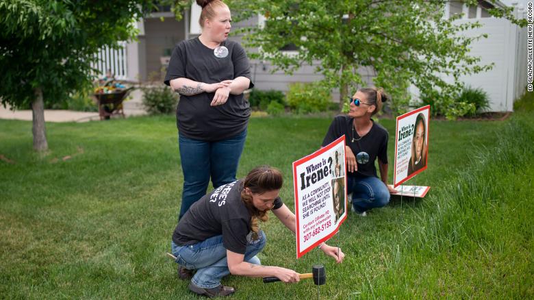 Lacey Ayers talks to Stacy Koester, left, and Melissa Bloxom as they place signs with an image of Irene Gakwa in a yard in Gillette, Wyoming. 