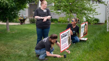 Lacey Ayers talks to Stacy Koester, left, and Melissa Bloxom as they place signs with an image of Irene Gakwa in a yard in Gillette, Wyoming. 