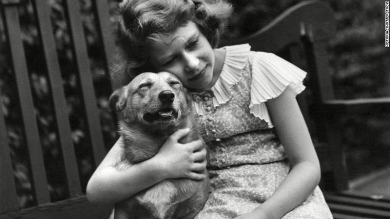 A young Elizabeth, then a princess, gives a corgi a comforting hug at her home in London in 1936.