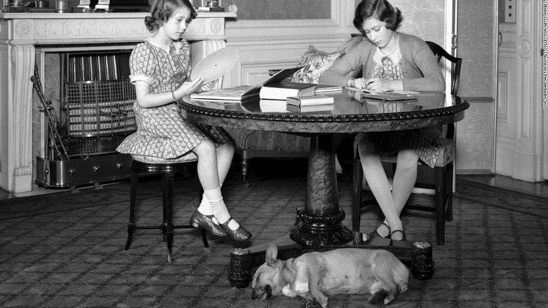 Elizabeth, right, and her sister, Princess Margaret, work at a desk while a corgi lies on the floor beside them at Windsor Castle in 1940. Elizabeth was officially gifted her own corgi by her parents on her 18th birthday in 1944.