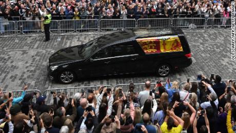 Members of the public watch the hearse carrying the coffin of Queen Elizabeth II as it is driven through Edinburgh toward the Palace of Holyroodhouse on Sunday