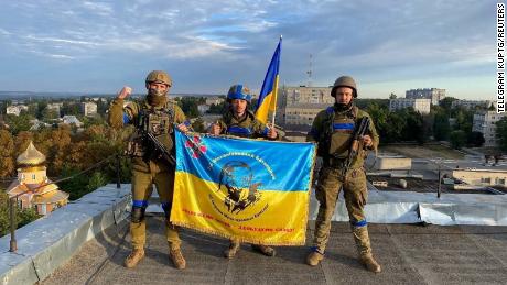 Украинские солдаты поднимают флаг на крыше здания в Кобянске, Украина, на этой фотографии, полученной из социальных сетей, опубликованной 10 сентября 2022 года. 