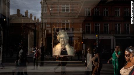 People walk past a portrait of the Queen inside a shop in central London.