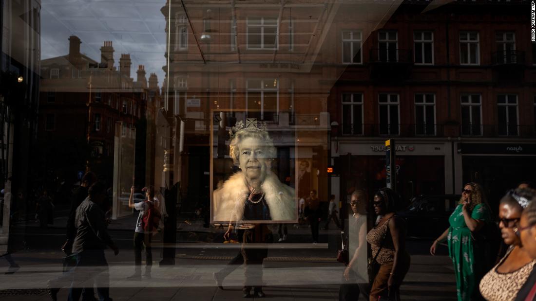 People in London walk past a portrait of the Queen on September 12.