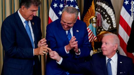 President Joe Biden hands the pen he used to sign the Democrats&#39; landmark climate change and health care bill to Manchin as Schumer looks on.