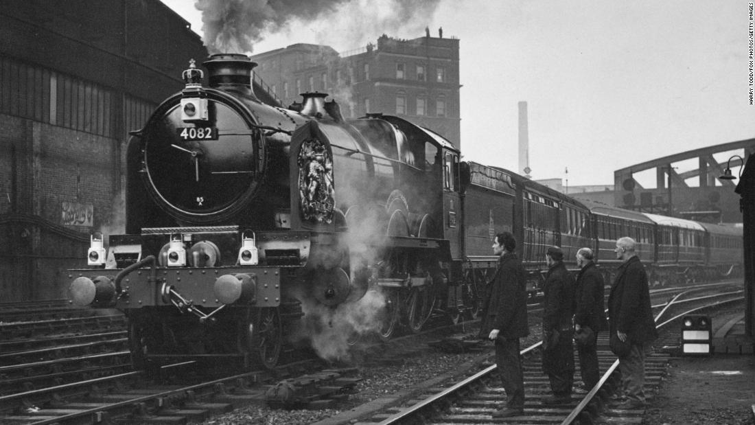 Railway workers pay their respects as the train carrying the King&#39;s coffin leaves Paddington station for Windsor. 