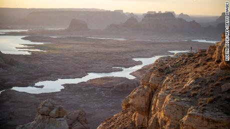 Visitors watch the sunrise over Lake Powell from Alstrom Point in Big Water, Utah, on September 3, 2022. - More than two decades of severe drought have left the Colorado River and its second largest reservoir, Lake Powell, at critical levels, as climate change leads to increased heat and decreased precipitation. In August the US government announced water supplies to some US states and Mexico will be cut to avoid a &quot;catastrophic collapse&quot; of the Colorado River. As of September 3, 2022, Lake Powell&#39;s water elevation was down to 3,531 feet, inching closer to dead pool status of 3,370 feet, the point at which the lakes water levels would be so low they would no longer flow downstream to power the hydroelectric power stations. (Photo by Robyn Beck / AFP) (Photo by ROBYN BECK/AFP via Getty Images)