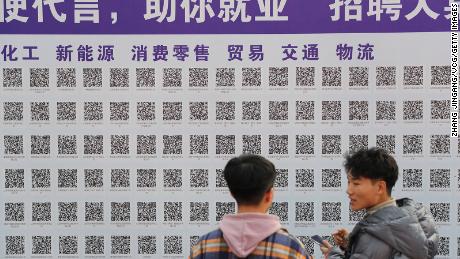 Üniversite öğrencileri, Çin'in Shandong Eyaleti, Qingdao'da 16 Kasım 2021'de Shandong Bilim ve Teknoloji Üniversitesi'nde düzenlenen bir iş fuarı sırasında iş fırsatları aramak için QR kodlarını tarıyor. 