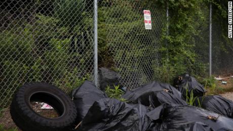 Discarded bags of trash are seen along a hole in a fence that leads into a proposed police development in Atlanta on August 15, 2022.