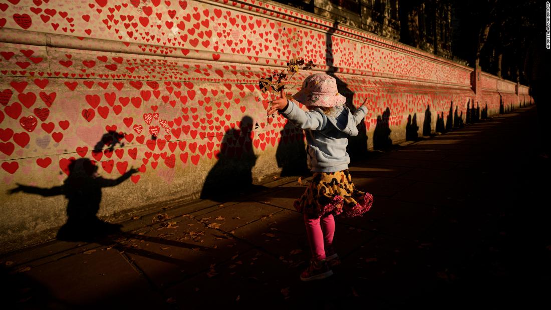 Ellie, 2, throws fallen leaves in the air as people wait in line to pay tribute to the Queen on Friday.