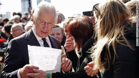 King Charles reacts as a member of the public hands him a drawing of his late mother as he meets people queuing to pay their respects as the Queen lays in state on September 17, 2022 .