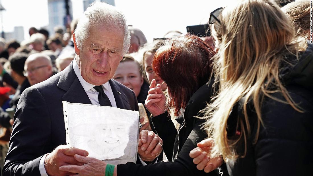 King Charles III reacts as a member of the public hands him a drawing of his mother on Saturday. The King and Prince William were shaking hands with people waiting in line to view the Queen&#39;s coffin.