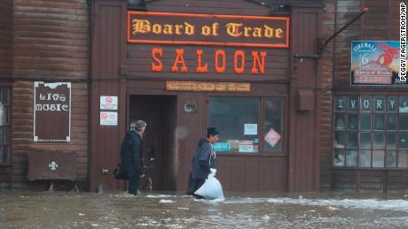 Two men walk through rushing water on Front Street, just a half block from the Bering Sea, in Nome, Alaska, on Saturday, Sept. 17, 2022. 